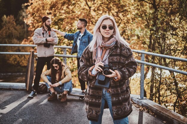 写真カメラで幸せな笑顔の女性は公園で明るい秋の日を楽しんでいます。