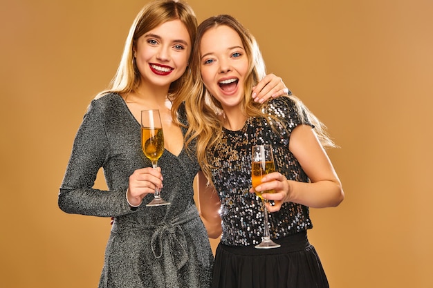 Free photo happy smiling women in stylish glamorous dresses with champagne glasses