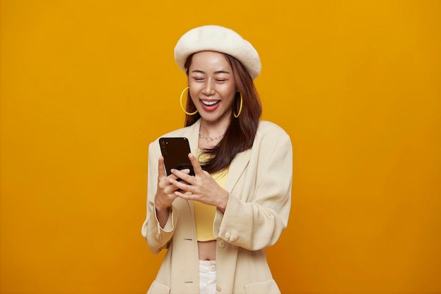 Счастливая улыбающаяся молодая азиатская женщина, использующая мобильный телефон, изолированный на y