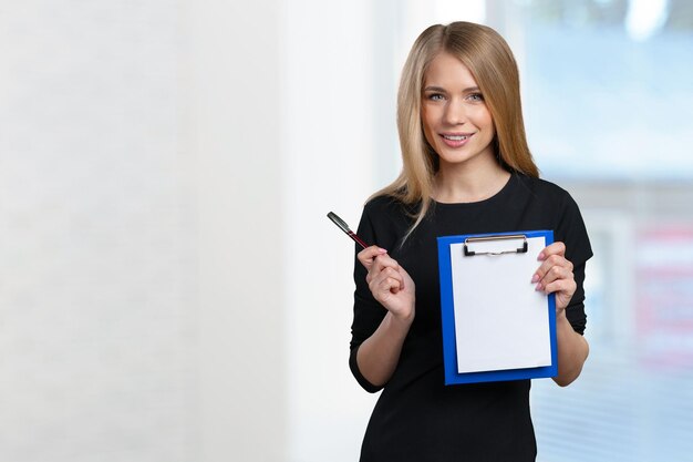 Happy smiling young beautiful business woman with clipboard