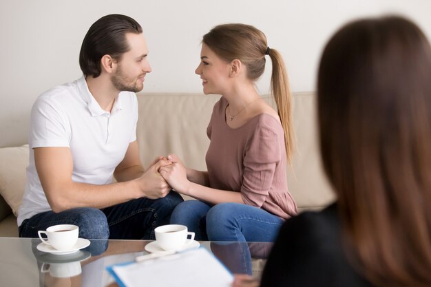 Happy smiling young couple holding hands, consulting psychologist, planning wedding