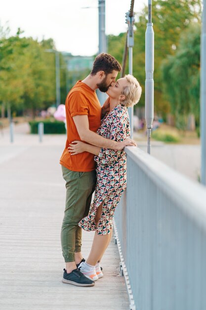 Happy smiling young couple hugging and kissing on bridge