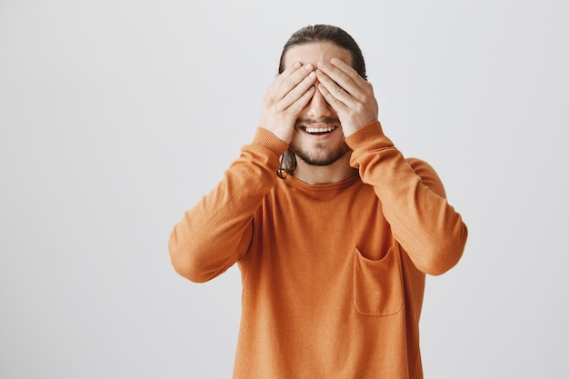 Foto gratuita felice sorridente giovane uomo chiudere gli occhi e in attesa di sorpresa