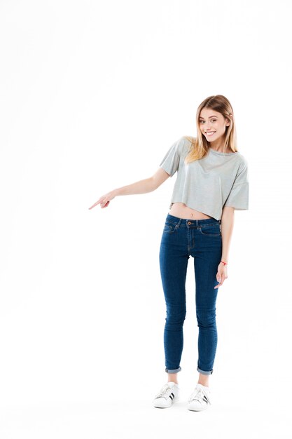 Happy smiling young woman standing and pointing