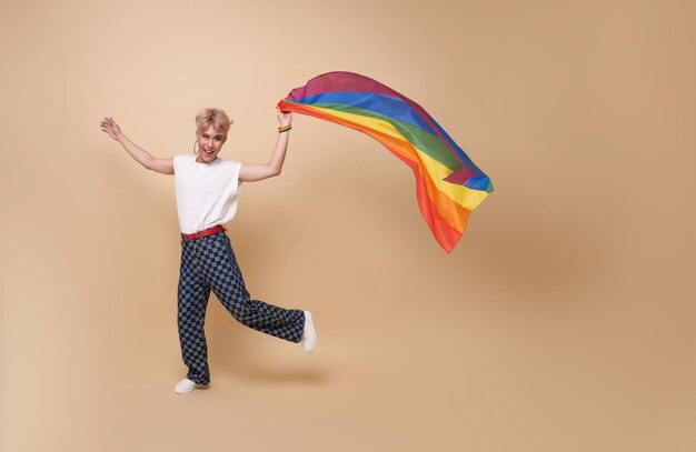 Счастливая улыбающаяся молодежь азиатская трансгендерная ЛГБТ скачет и размахивает флагом радуги