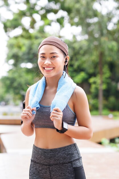 Happy sportive woman with gadget in park