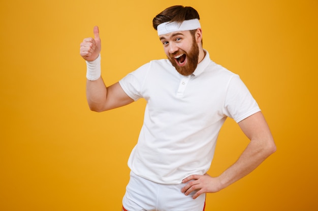 Happy sportsman showing thumb up holding arm at hip