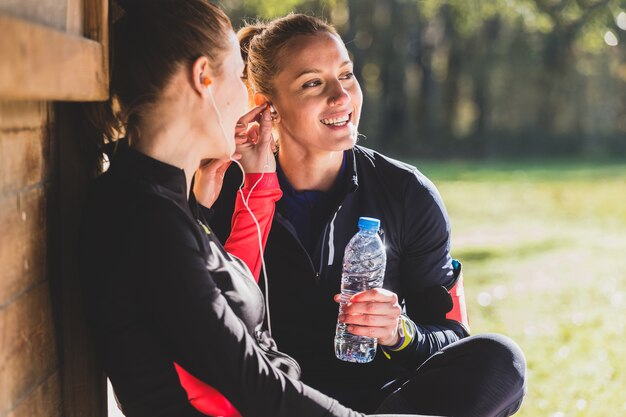 Happy sportswoman listening to music and holding a bottle