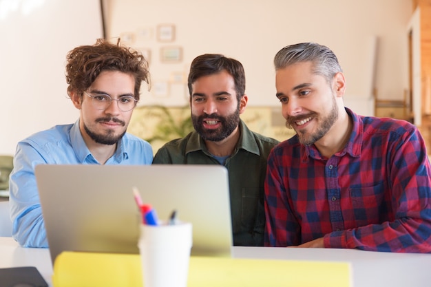 Happy startup team watching presentation on monitor