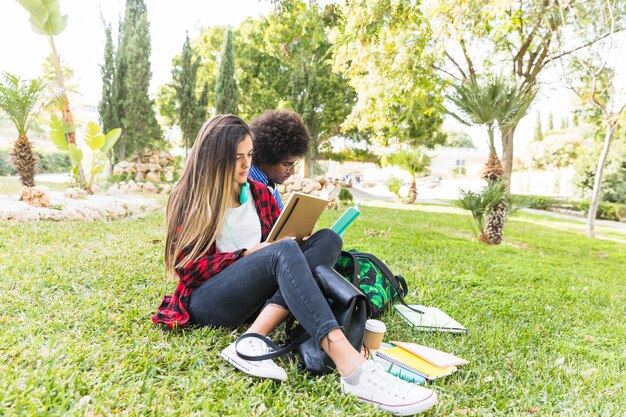 Happy student couple reading book in park on spring day