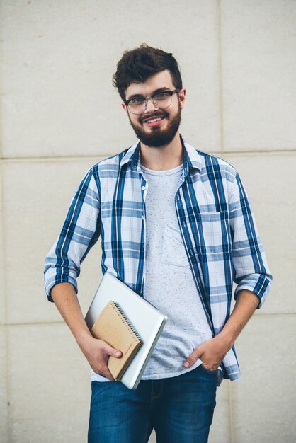 Happy student posing on camera  holding texrbooks outdoors