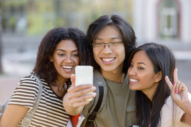 幸せな学生が立って、屋外でselfieを作る