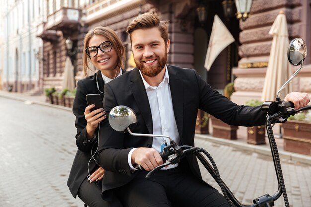 Happy stylish couple rides on modern motorbike outdoors