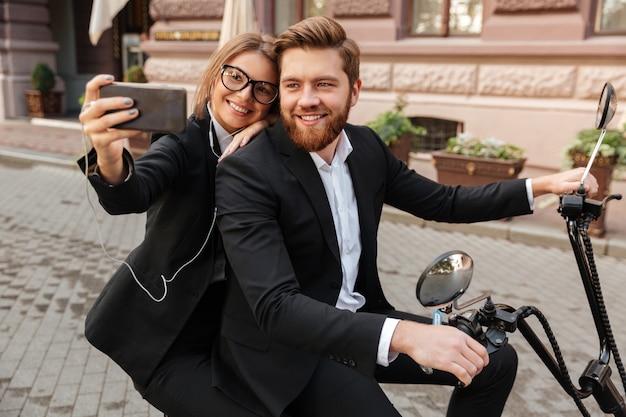 Happy stylish couple sitting on modern motorbike outdoors