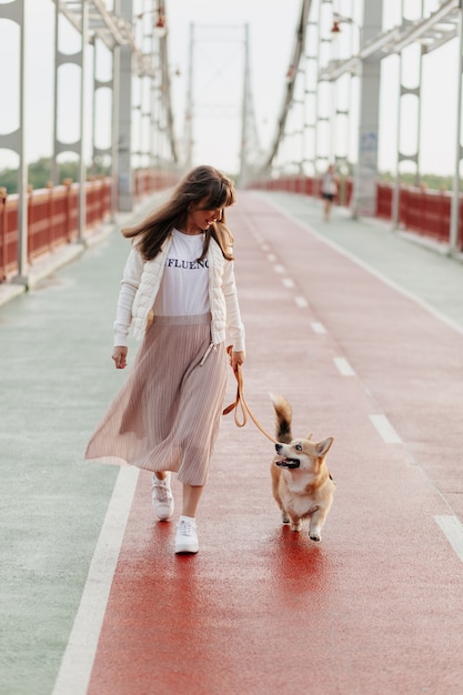 Happy stylish woman walking with her corgi