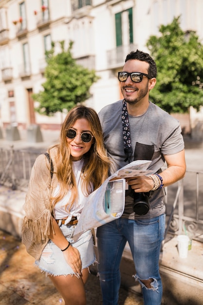 Happy stylish young couple holding map