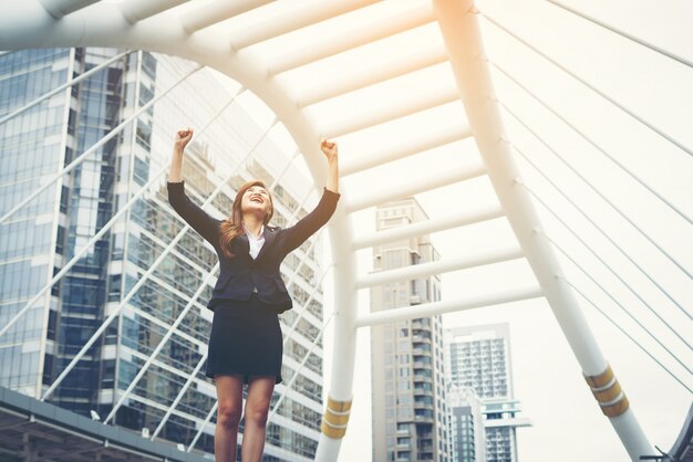 Happy Success Businesswoman overlooking into the city center hands raised.