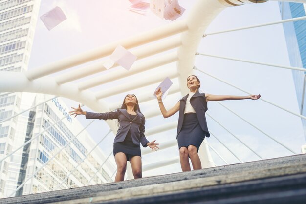 Happy Success Businesswomen overlooking jummping into the city center hands raised.