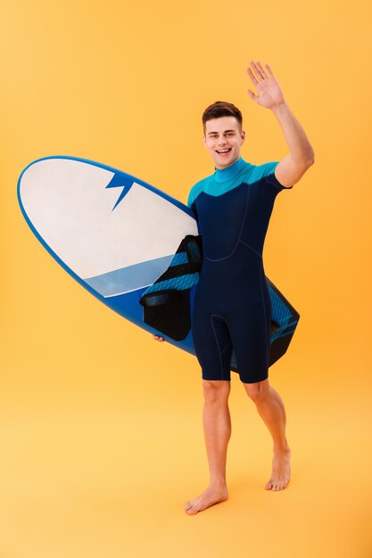 happy surfer walking with surfboard