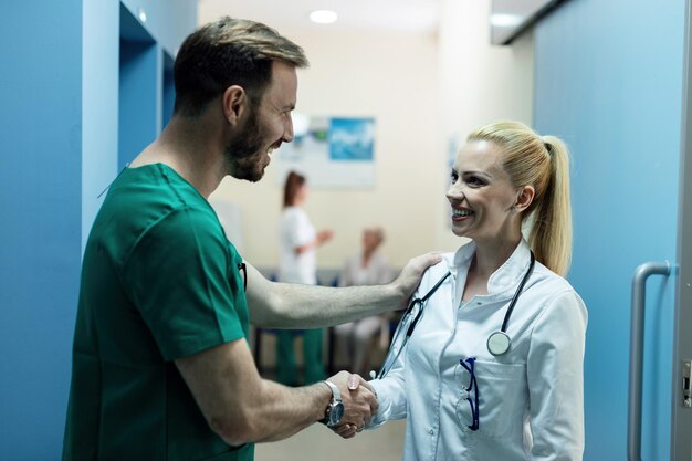 Happy surgeon and female doctor greeting in a hallway at clinic Focus is on female doctor