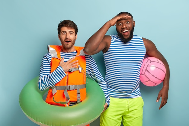 Foto gratuita felice sorpreso diversi giovani uomini vestiti con maglietta da marinaio e pantaloncini, tenere palla da spiaggia