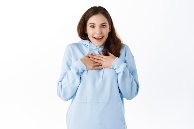 Happy surprised girl receive surprise gift holding hands on chest and gasping amazed thanking you being grateful appreciate nice gesture standing against white background