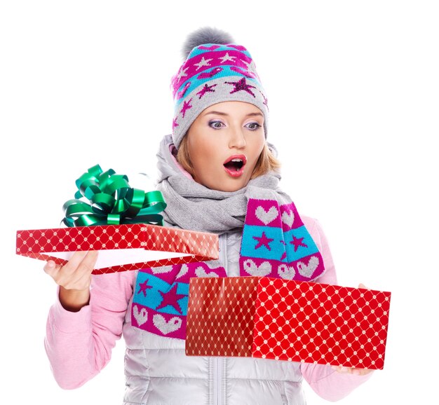 счастливая удивленная женщина с рождественским подарком в зимней верхней одежде изолирована на белом