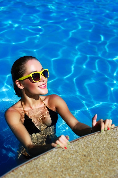 Happy tanned girl posing in the pool