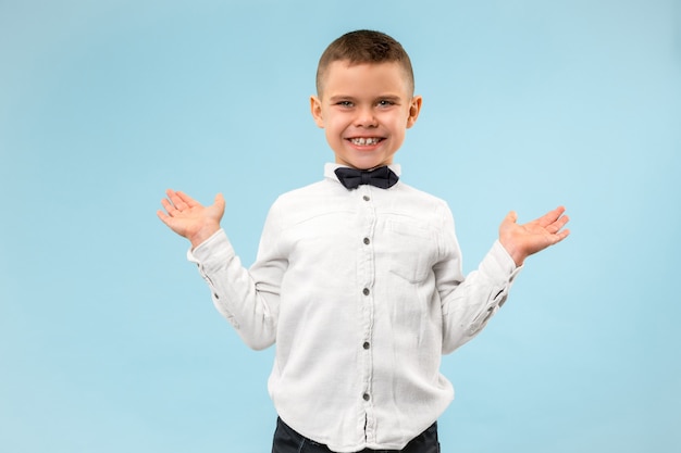 Free photo the happy teen boy standing and smiling against blue background.