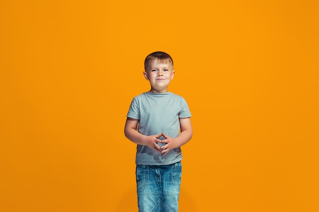 Free photo the happy teen boy standing and smiling against orange space.