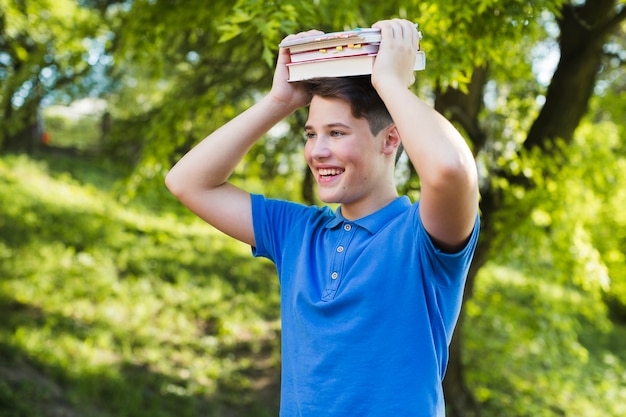 Happy teen boy with books on head