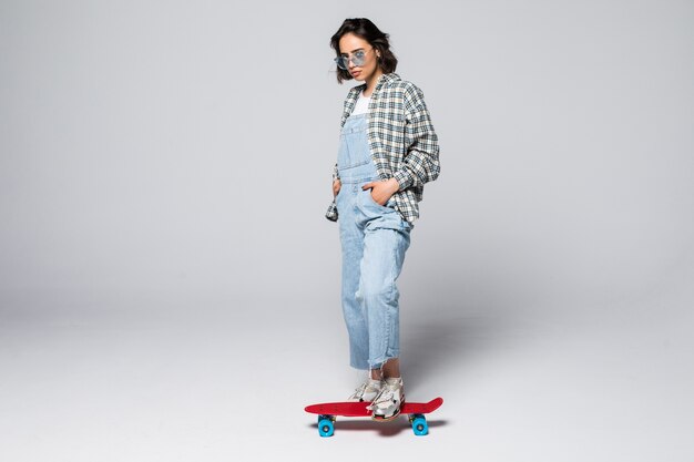 Happy teen girl in full length holding skate board looking to the side at blank copy space, isolated