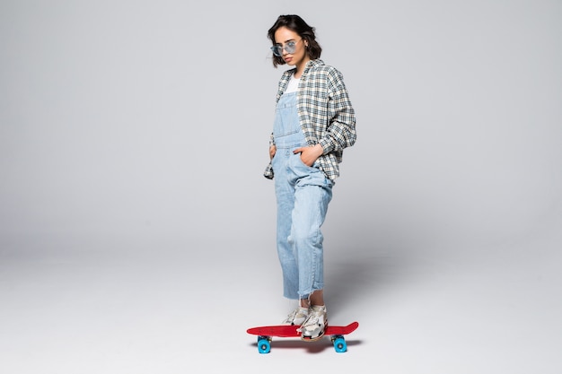 Happy teen girl in full length holding skate board looking to the side at blank copy space, isolated