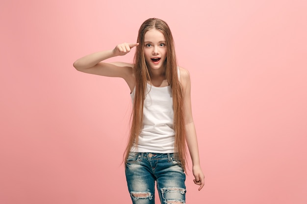 The happy teen girl pointing to you, half length closeup portrait on pink.