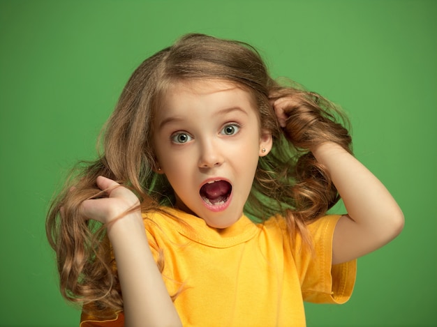 The happy teen girl standing and smiling against green background.