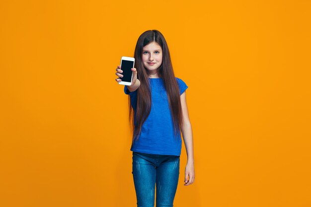 The happy teen girl standing and smiling against orange.