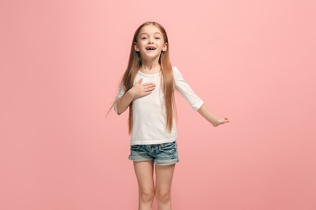 Foto gratuita la ragazza adolescente felice in piedi e sorridente contro il muro rosa