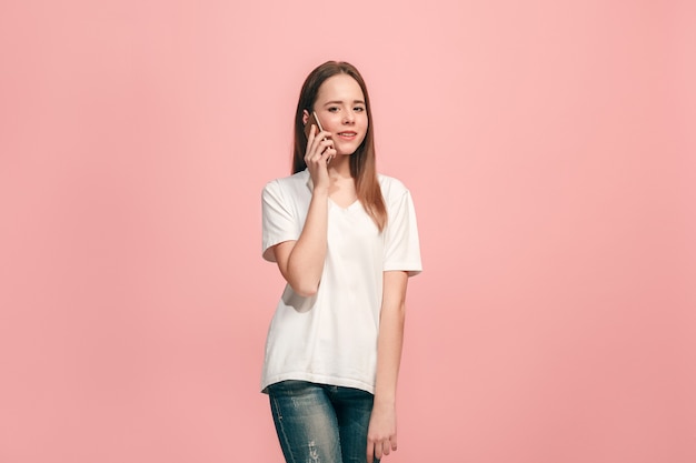 The happy teen girl standing and smiling against pink.