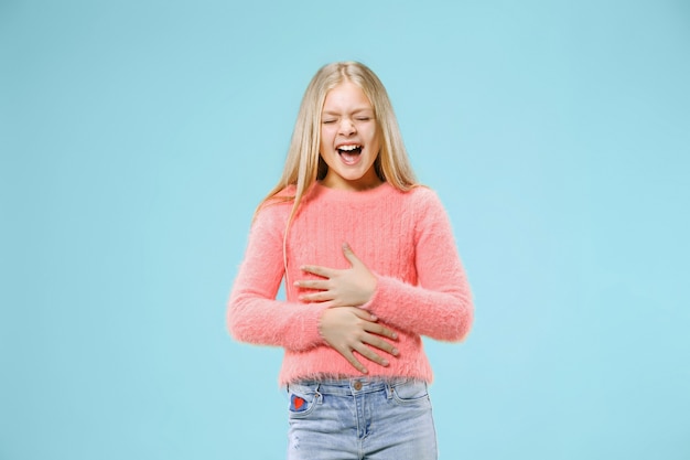 Happy teen girl standing, smiling isolated on trendy blue studio background. Beautiful female portrait.