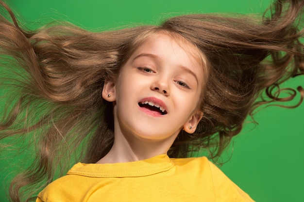 Felice ragazza adolescente in piedi, sorridente isolato sul verde alla moda. bellissimo ritratto femminile.