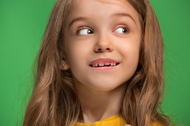 Ragazza teenager felice in piedi, sorridente isolato su studio verde alla moda.