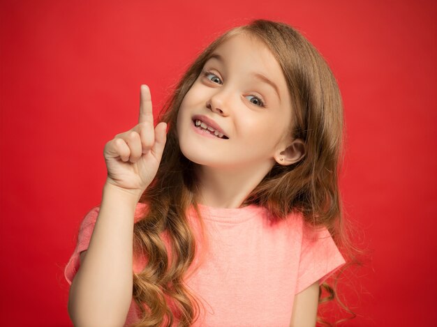 Happy teen girl standing, smiling isolated on trendy red studio wall