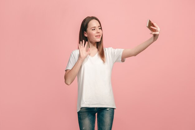 Happy teen girl standing, smiling on pink studio