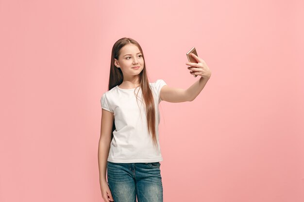 Happy teen girl standing, smiling on pink studio