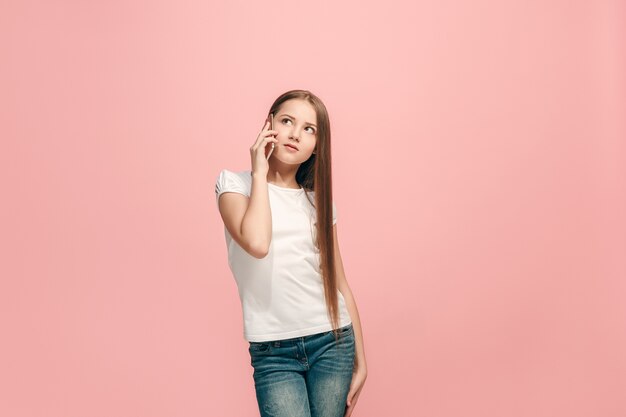 Happy teen girl standing, smiling with mobile phone over trendy pink studio