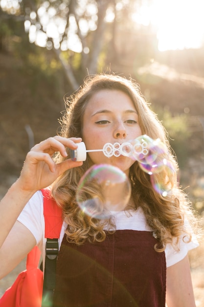 Free photo happy teenager blowing bubbles in park