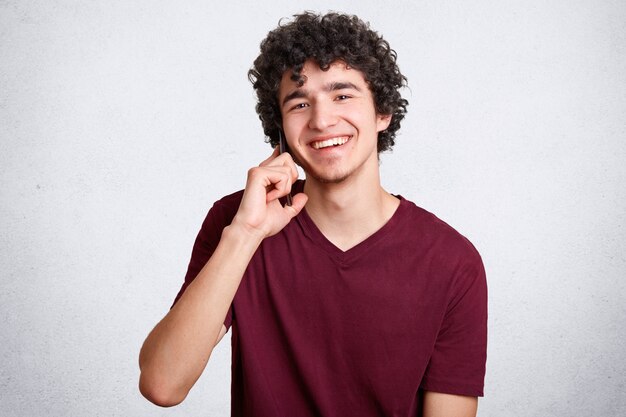 Happy teenager or hipster guy, speaks via cell phone with best friend