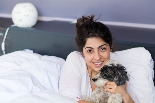 寝室で彼女の犬と一緒にポーズを取るハッピーティーンエイジャー