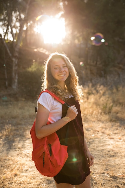 Happy teenager with backpack grinning in countryside