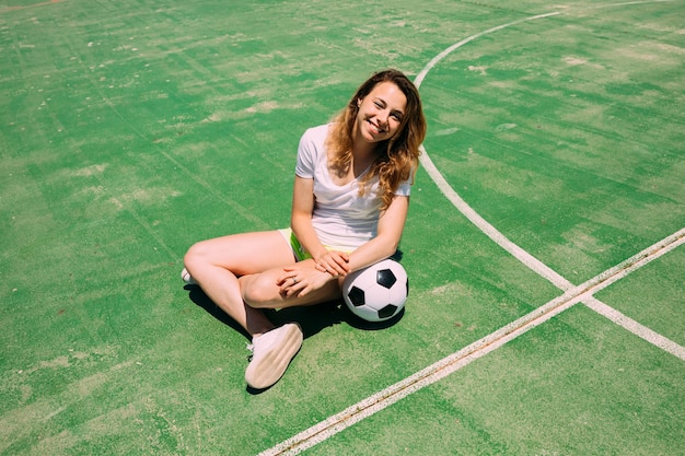 Happy teenager with ball on football pitch